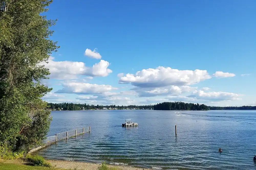 Sunny view across American Lake from a grassy shore with a small dock in Lakewood, Washington