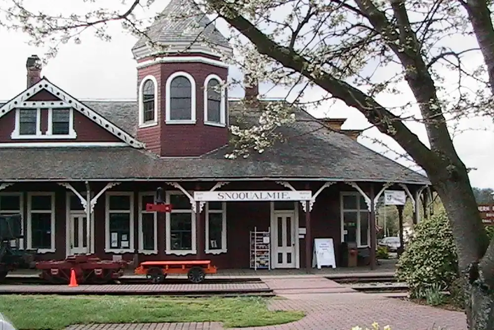 Historic red Snoqualmie depot with a cupola and a flowering tree in Snoqualmie, Washington